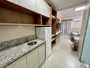 Una cocina compacta con encimera de granito, pileta de acero inoxidable y refrigerador blanco.