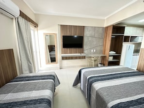 Ein Hotelzimmer mit zwei Betten, einem Fernseher, einem Schreibtisch und einem Kleiderschrank.