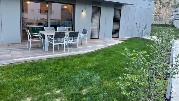 Una casa moderna con patio attrezzato con tavolo e sedie, prato curato e vista sul paesaggio circostante.