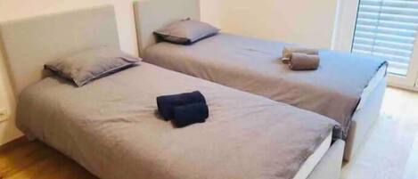 Una habitación con dos camas individuales, cada una con una almohada y una manta.