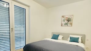 Una camera da letto con un letto, una finestra con tende, una luce a soffitto e un'opera d'arte appesa al muro.