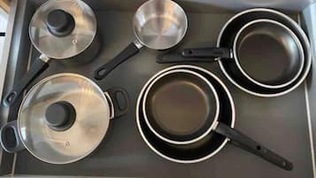 Uma cozinha com fogão, panelas e frigideira.