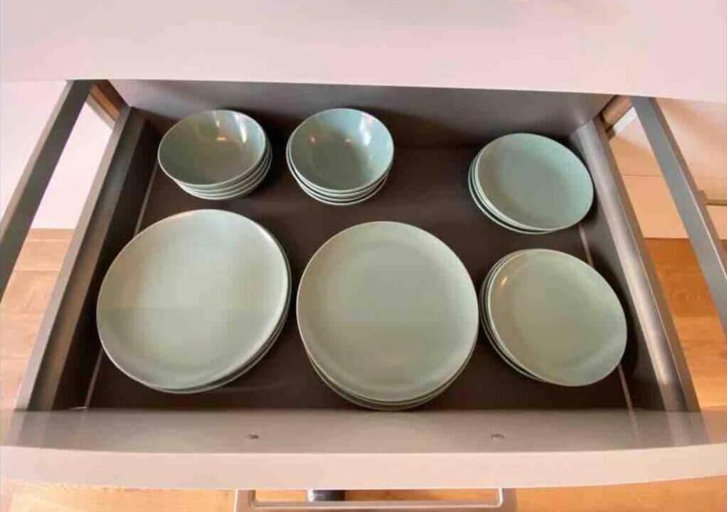 A kitchen drawer with six stacked plates.