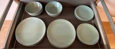A kitchen drawer with six stacked plates.