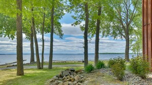 A lakeside property with a fire pit, trees, and a view of the water. - Lake Champlain Vacation Rental with Boat Dock! (St. Albans Town)