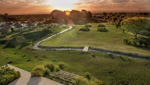 Un parcours de golf agrémenté d’un plan d’eau, entouré d’arbres et offrant une vue sur un ciel dégagé.