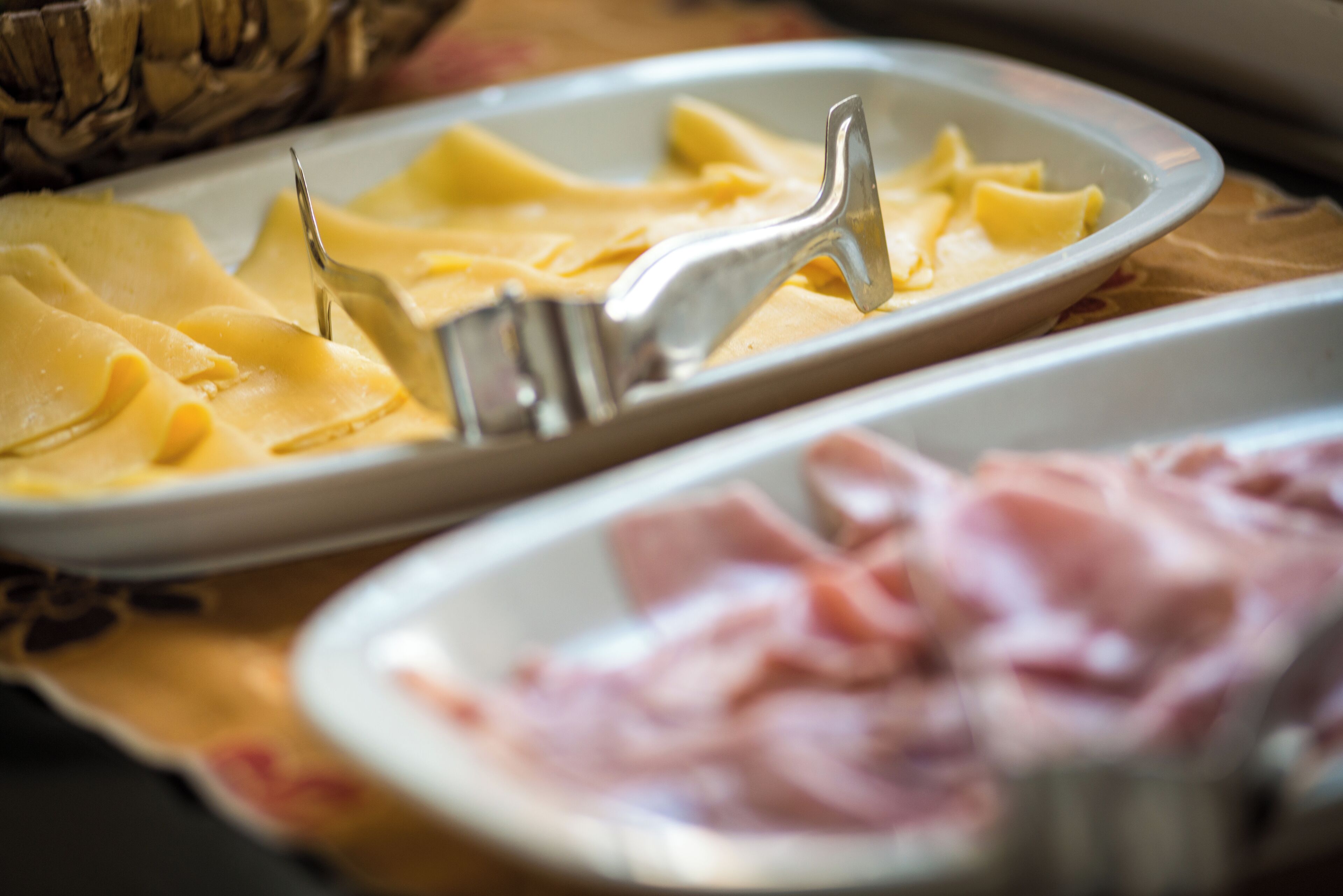 Una mesa de comedor con platos de comida, incluyendo pasta y jamón.