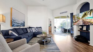 Una sala de estar moderna con un sofá modular, una mesa de centro redonda y una pantalla de televisión grande.