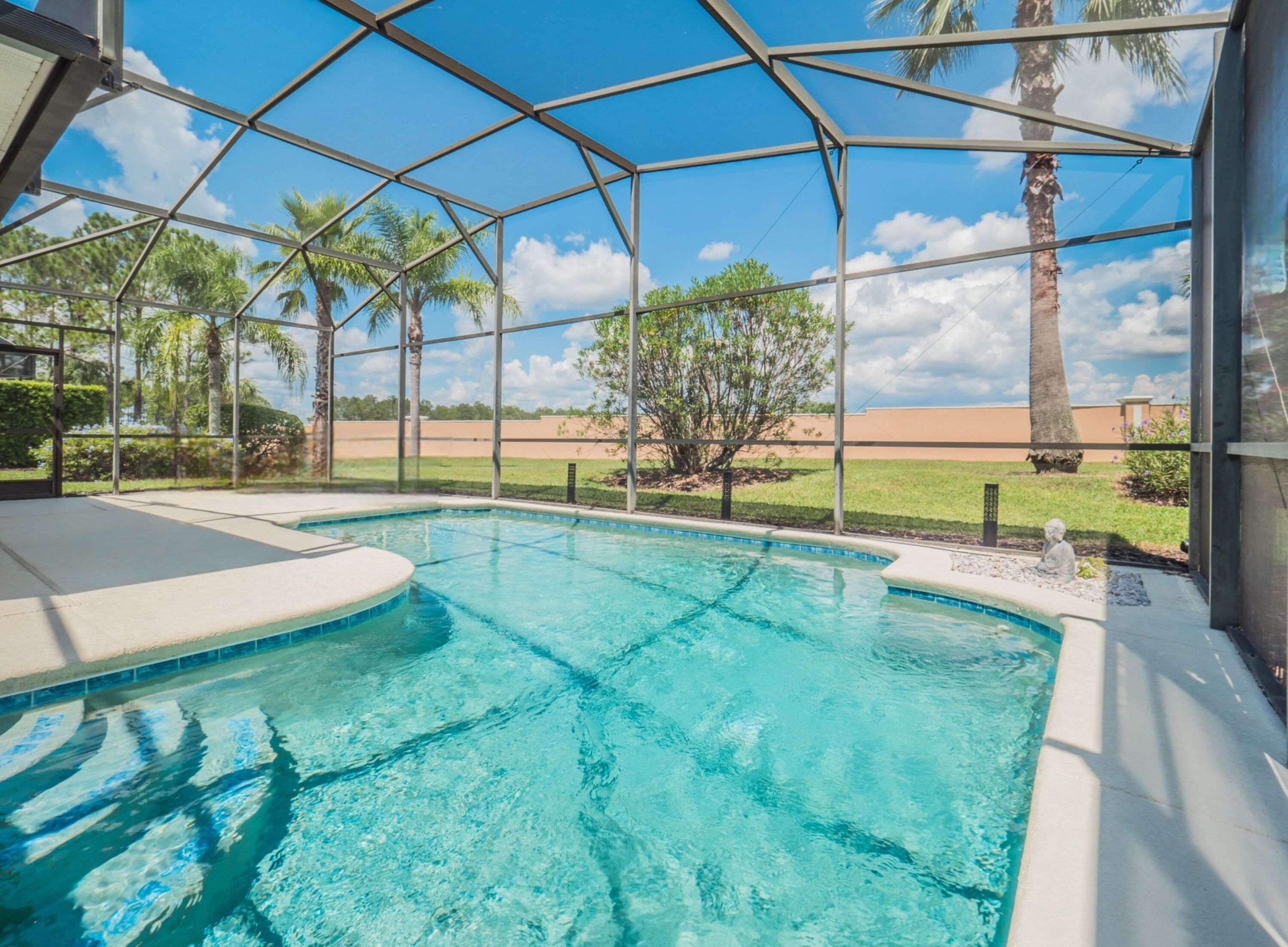 A swimming pool with a clear view of the surrounding landscape, including palm trees and a distant building.