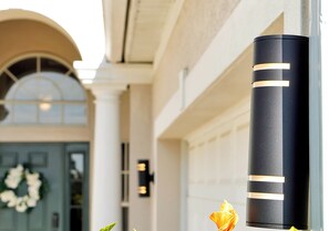 A black cylindrical object with gold stripes, possibly a decorative item, mounted on a wall.