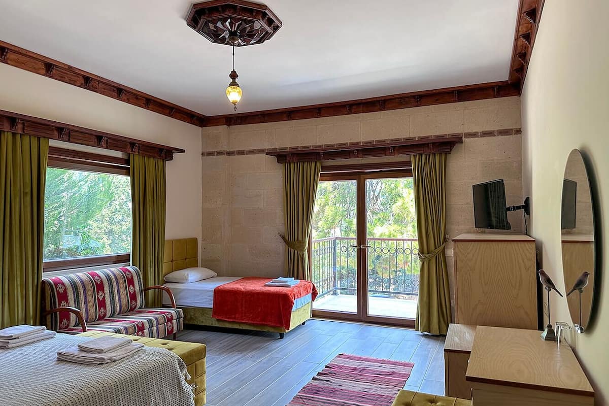 A bedroom with a bed, a sofa, a desk, and a balcony.