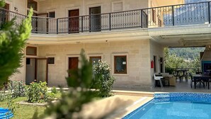 Un bâtiment à deux étages doté d’une piscine, d’un espace extérieur aménagé et offrant une vue sur les montagnes.