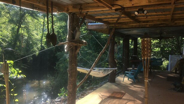 Een overdekte buitenruimte met een hangmat, een tafel en stoelen.