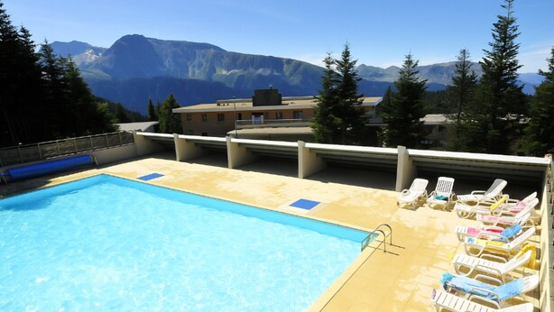 A swimming pool with lounge chairs and a view of mountains.