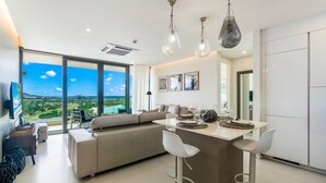 A modern kitchen with a large island, bar stools, and a view of the outdoors. - A-1102 Spacious and modern two bedroom with oceanview (Cupecoy)
