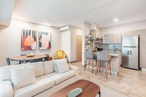 Een moderne woonkamer met een bank, salontafel en een eethoek met stoelen.