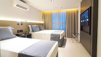 Habitación de hotel con dos camas, televisión, aire acondicionado y una ventana con cortinas.