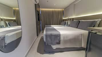 Ein modernes Hotelzimmer mit einem großen Bett, einem Nachttisch, einem Spiegel und einem Fernseher.