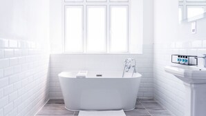 A modern bathroom with a freestanding bathtub, white tiled walls, and a window. - The Woodman Hotel (London)