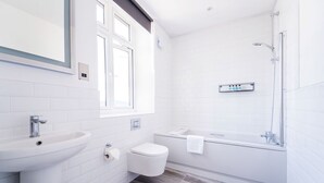 A modern bathroom with a sink, toilet, and bathtub. - The Woodman Hotel (London)