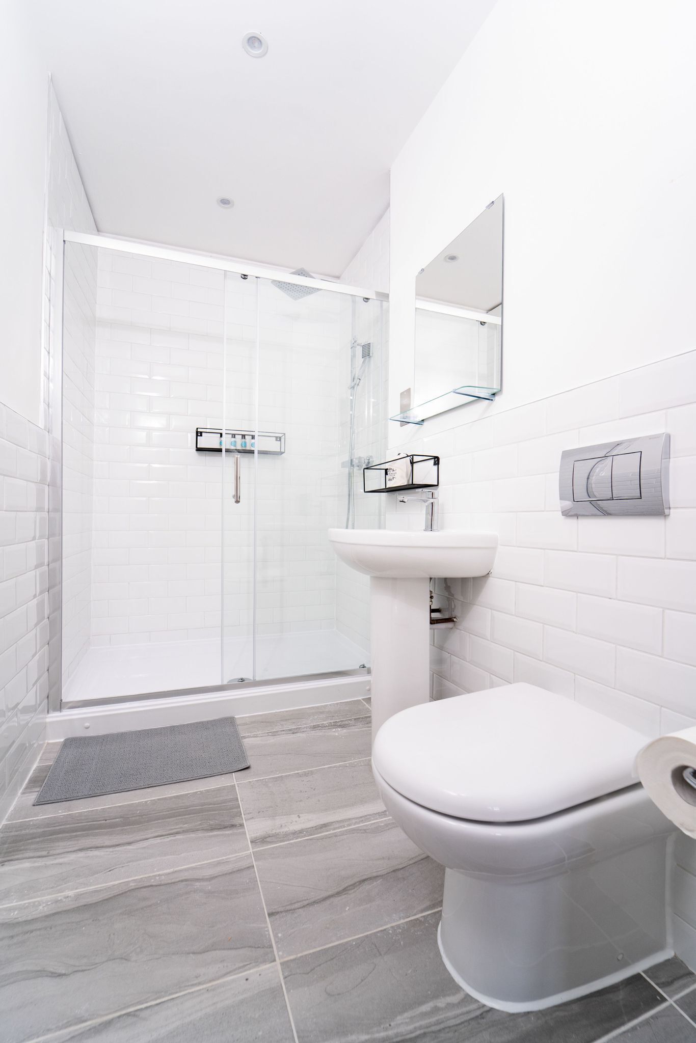 A modern bathroom with a glass-enclosed shower, a white sink, and a toilet.
