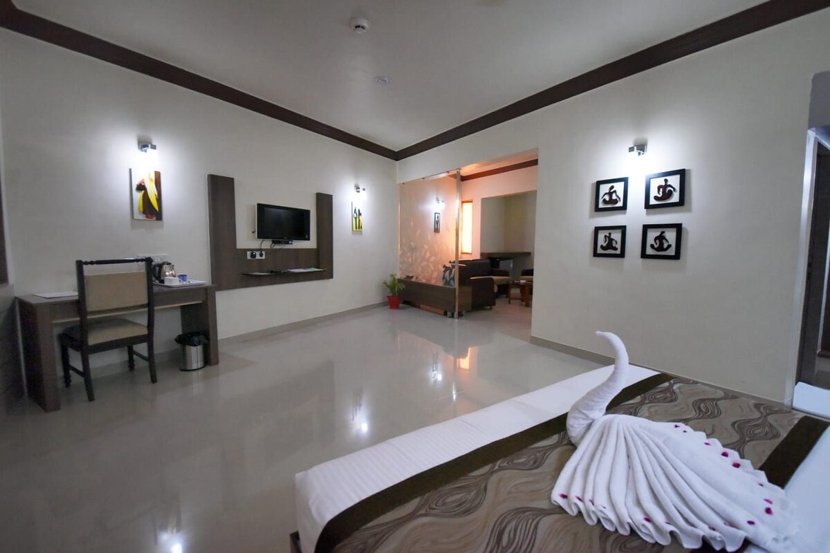 A hotel room with a bed, a desk, a television, and a seating area with a sofa and chairs.