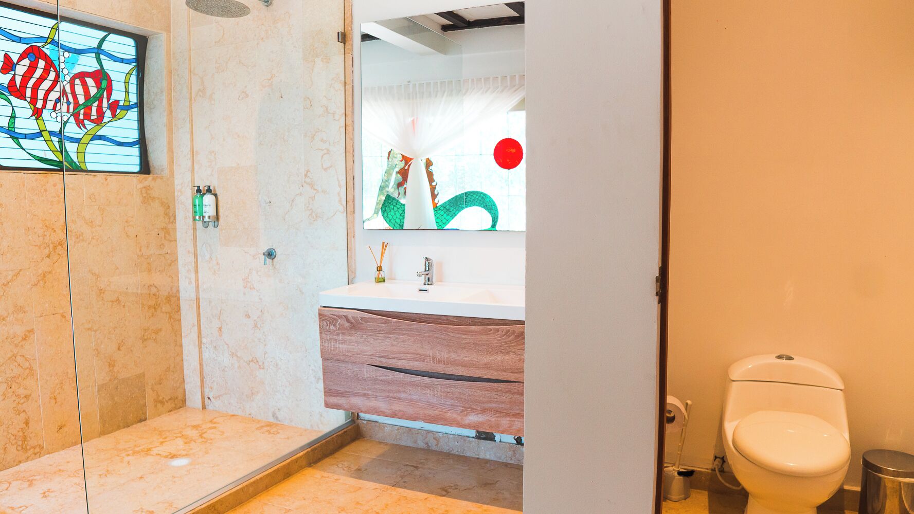 A bathroom with a shower, a sink with a mirror, and a toilet.