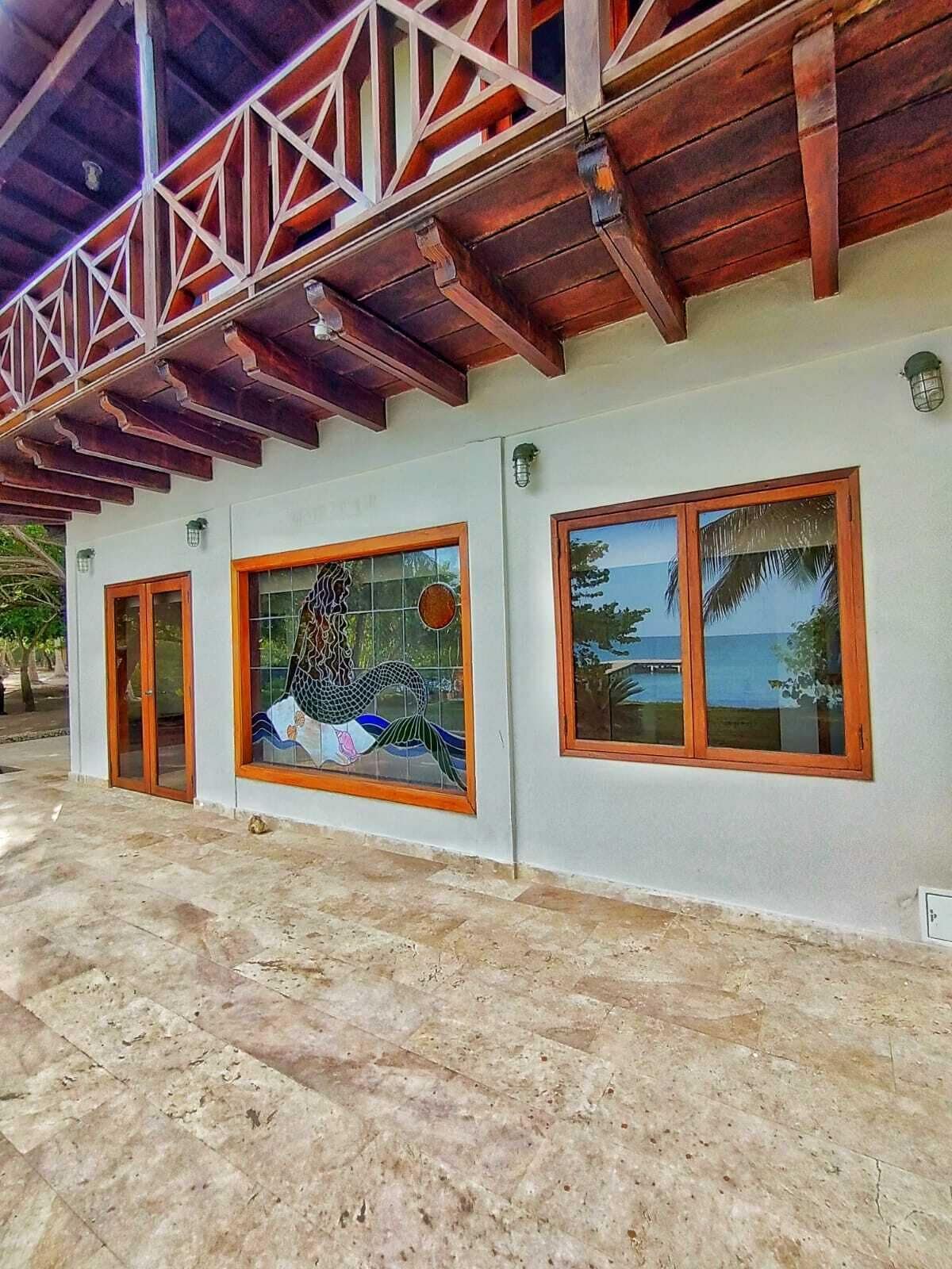 A building with a tiled floor, wooden beams, and large windows with wooden frames.