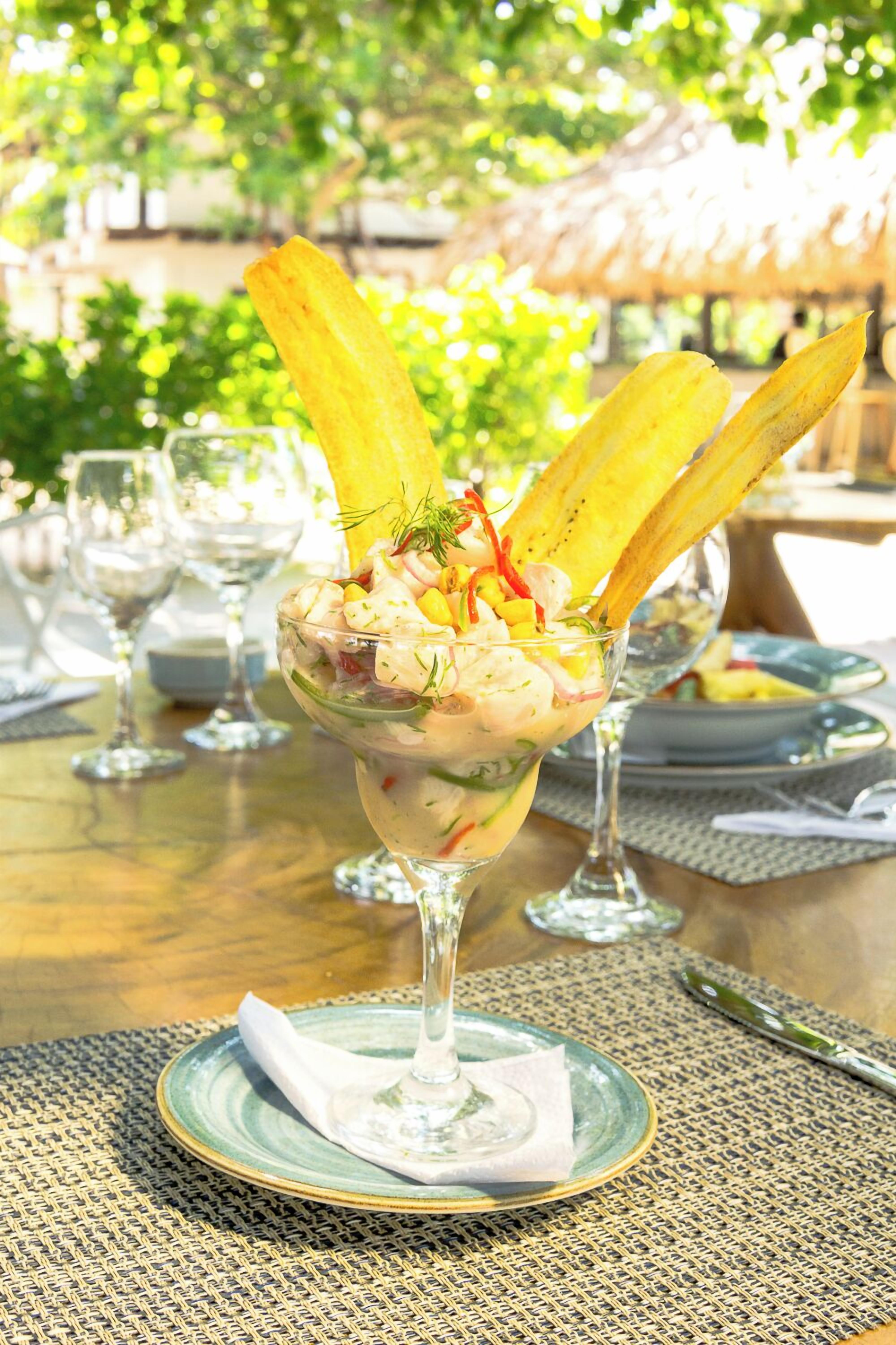 A glass dessert bowl on a table with a woven placemat underneath.