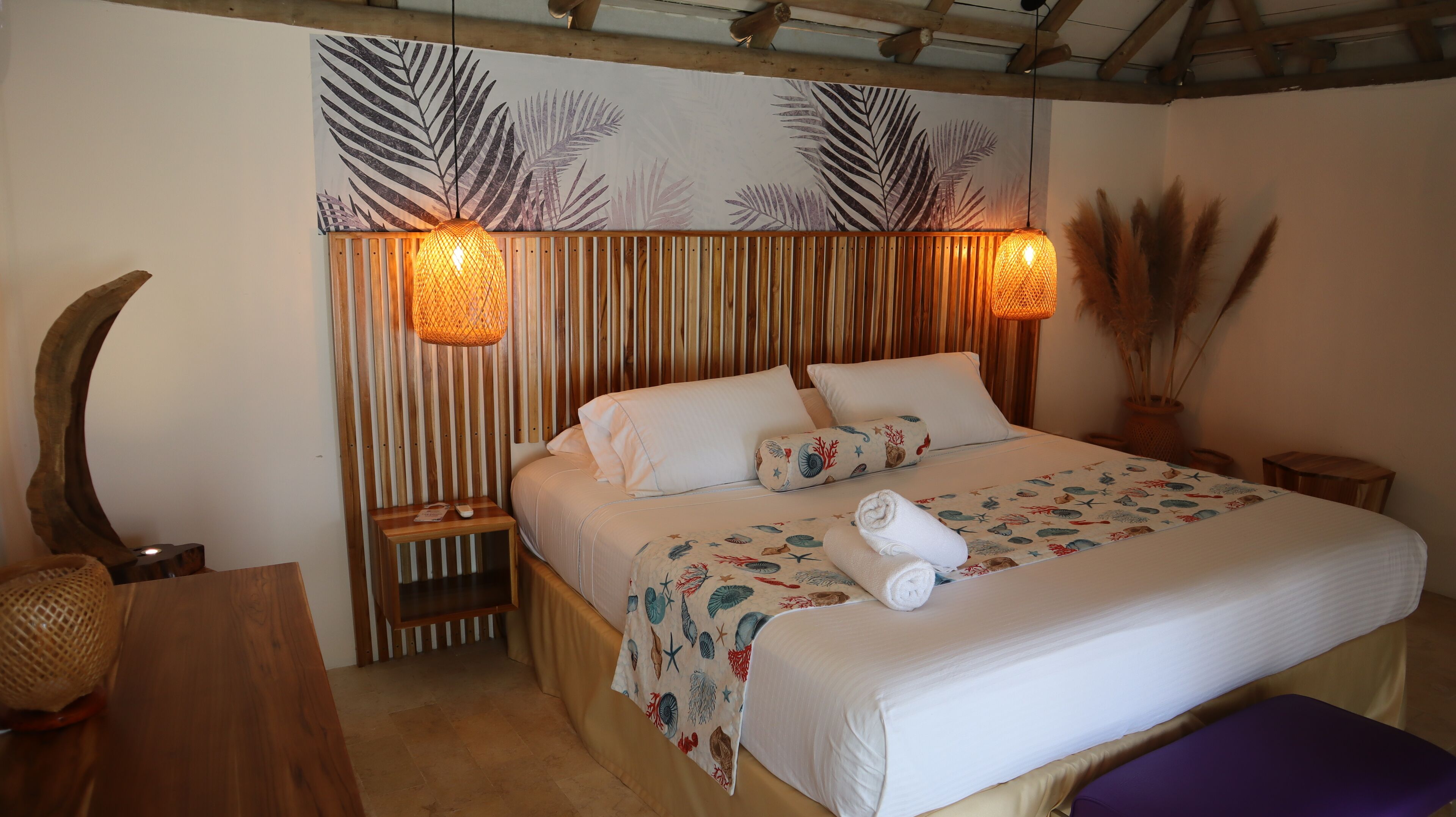 A neatly made bed with a floral bedspread, two bedside tables with lamps, a wooden headboard, and a large mirror.
