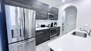 A modern kitchen with stainless steel appliances, dark wood cabinets, and a white countertop. - Balmoral Resort-213al 3 Bedroom Home by RedAwning (Haines City)