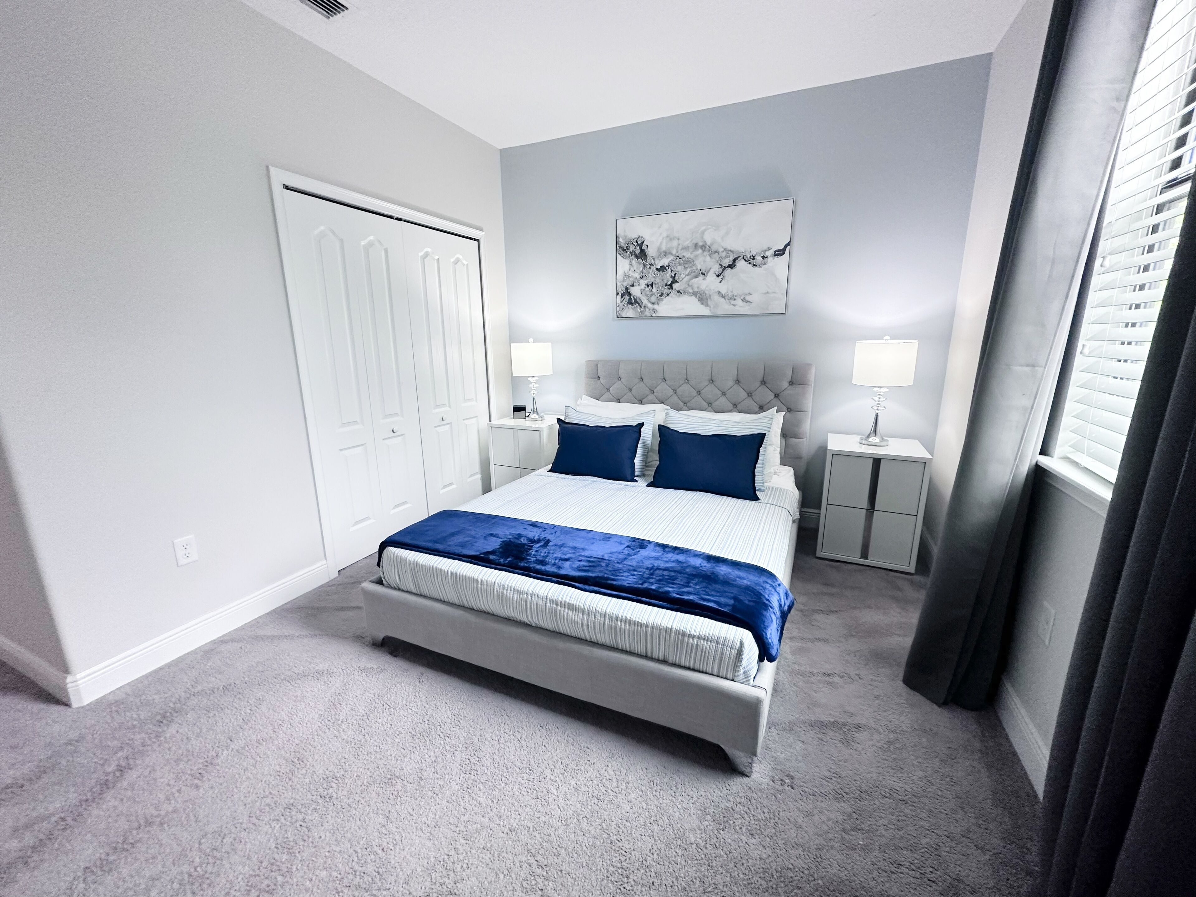 Ein Schlafzimmer mit einem großen Bett, zwei Nachttischen, einem Kleiderschrank und einem Bild an der Wand.