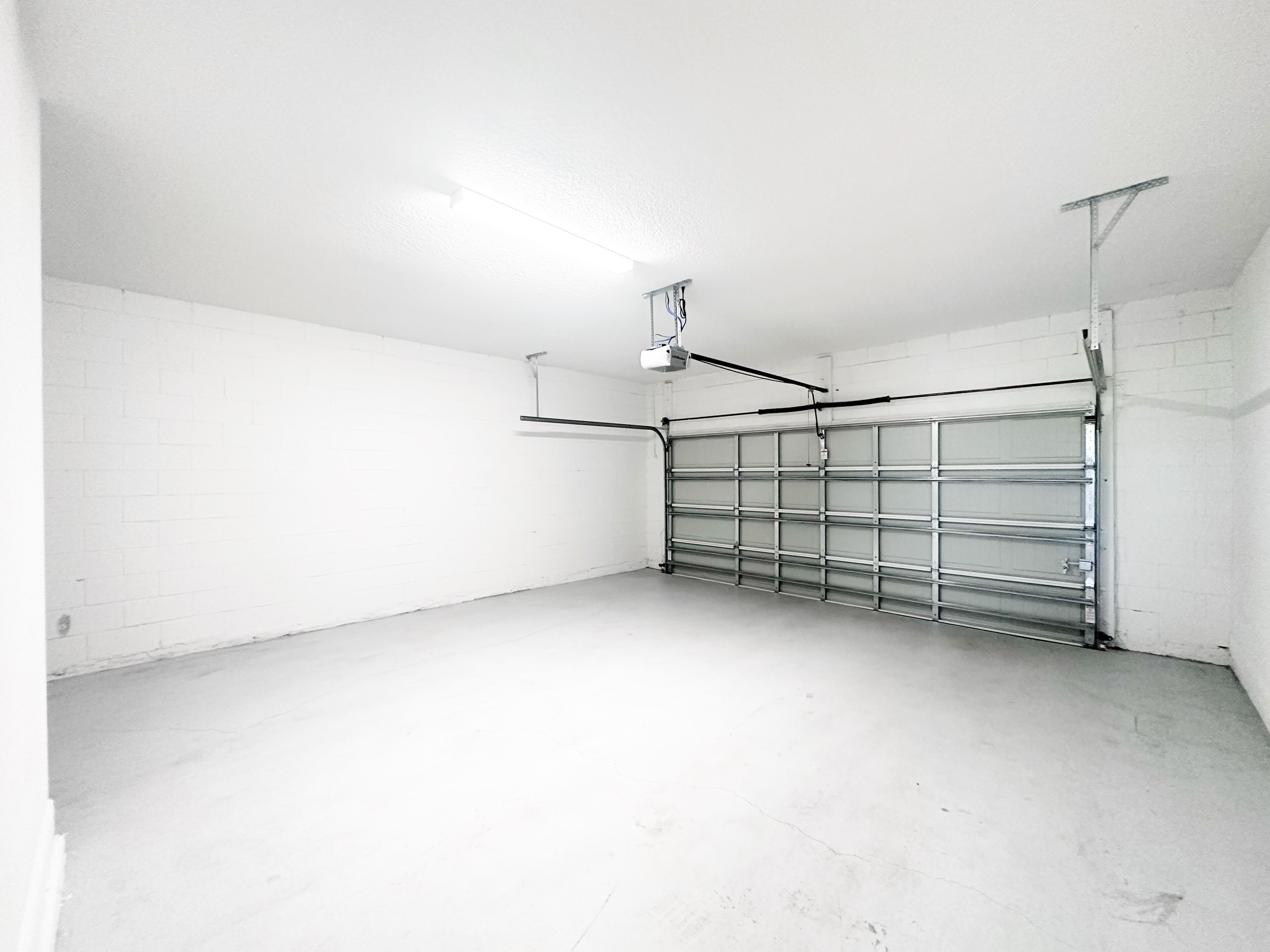 Un garage propre et vide, avec des murs blancs et une porte de garage en métal.