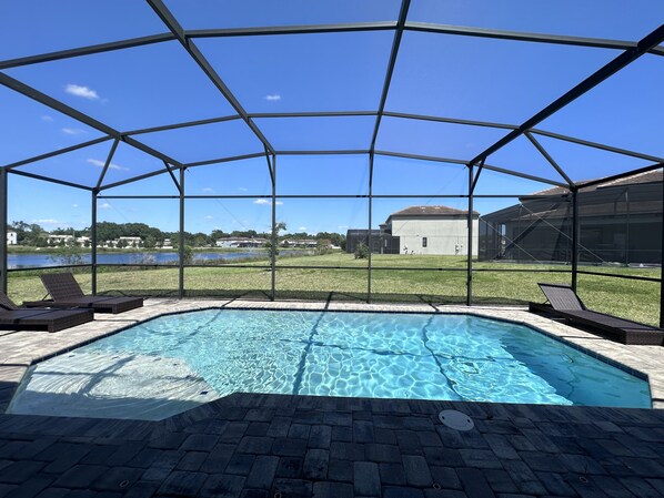 Una piscina cubierta al aire libre con vistas a un lago y casas al fondo.