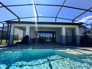 Un área de piscina exterior cubierta con un patio y asientos.