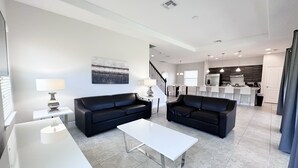A modern living room with two black sofas, a white coffee table, and a dining area in the background. - Balmoral Resort-210bp 4 Bedroom Home by RedAwning (Haines City)