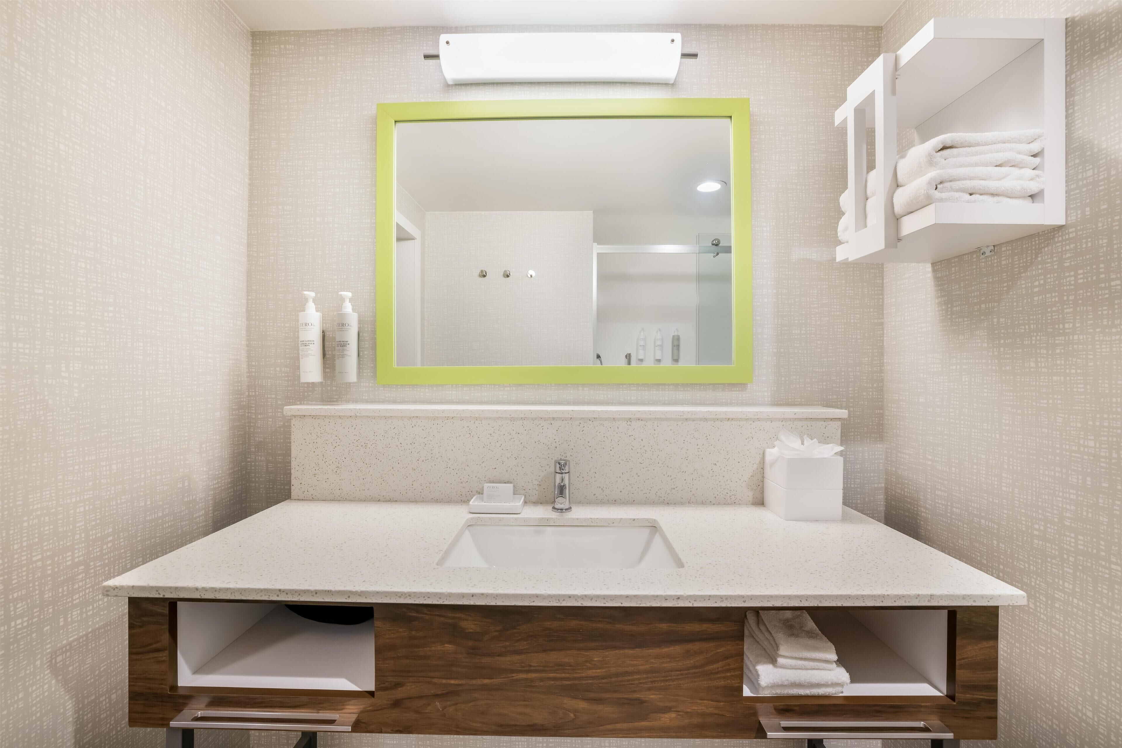 A modern bathroom with a large mirror, a sink, and a towel rack.