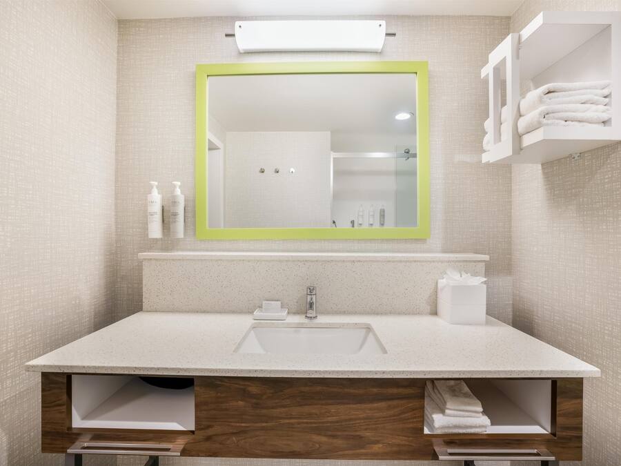 Un baño moderno con un espejo grande, un lavamanos y un perchero para toallas.