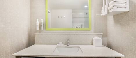 A modern bathroom with a large mirror, a sink, and a shower area.