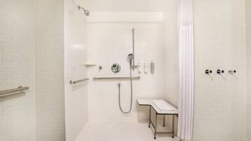 A walk-in shower with a handheld showerhead, a handheld shower attachment, a handheld scrubber, and a handheld dryer.