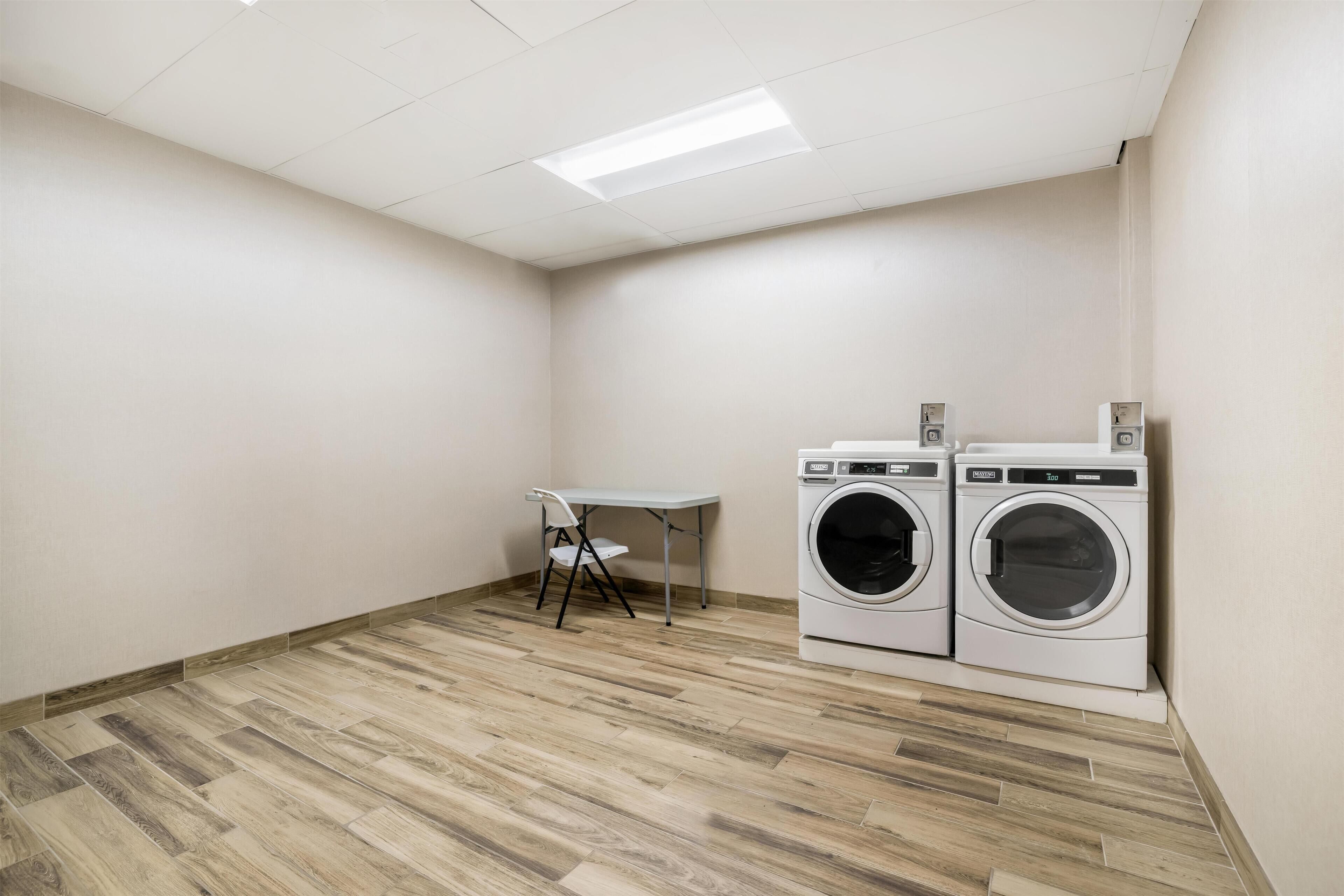 A laundry room with two washing machines, a folding table, and a bench.