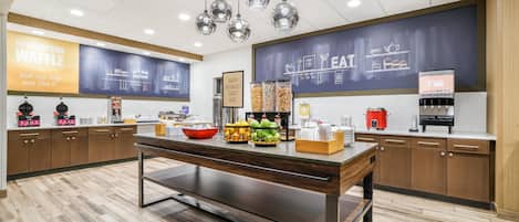 Un espace cuisine moderne doté d’un bar pour prendre le petit-déjeuner, d’un présentoir à fruits et d’un tableau noir servant de menu.