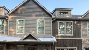 A two-story house with a stone facade, a red door, and a garage. - Downtown Clayton Townhouse (Clayton)