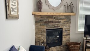 A living room with a stone fireplace, a blue sofa, a mirror, and a framed inspirational quote. - Downtown Clayton Townhouse (Clayton)