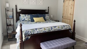 A bedroom with a wooden bed, a bench, a bedside table, a lamp, and a wardrobe. - Downtown Clayton Townhouse (Clayton)