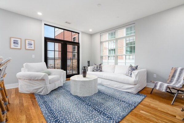 Un salon moderne avec un canapé blanc, une table basse ronde et un tapis à motifs bleus.