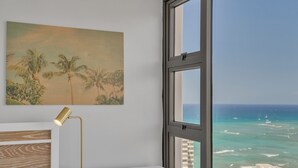 A hotel room with a large window offering a view of the ocean and palm trees. - Beach Oasis with Ocean & City Views with FREE Parking! (Honolulu)