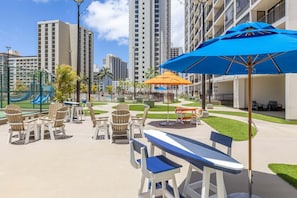 A rooftop patio with outdoor seating, a pool, and high-rise buildings in the background.