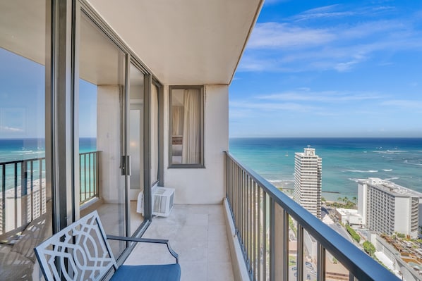A balcony with a view of the ocean and cityscape.