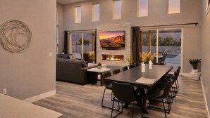 Una sala de estar moderna con chimenea, comedor y un amplio ventanal con vistas panorámicas.